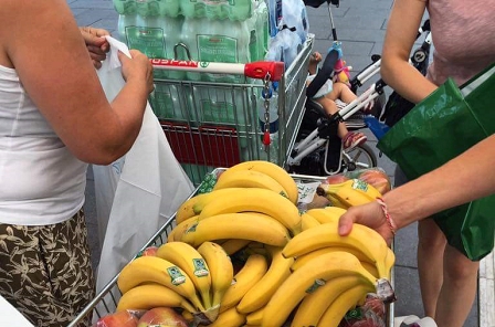 Viele Bananen in einem Einkaufswagerl und Wasserflaschen