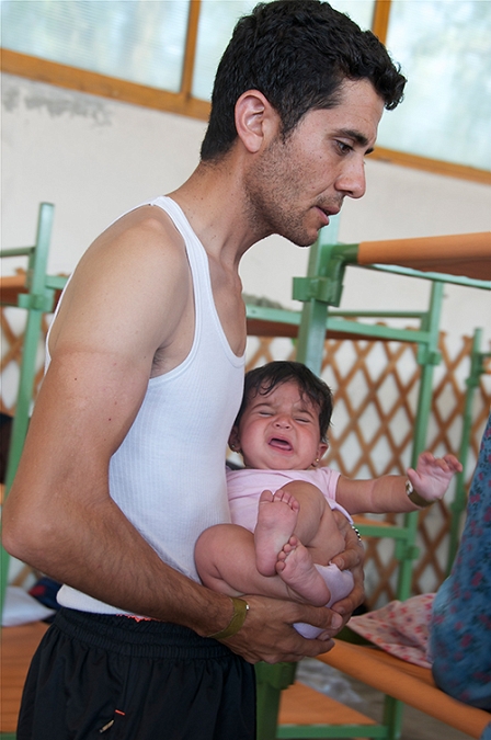 Junger Mann mit schreiendem Baby am Arm