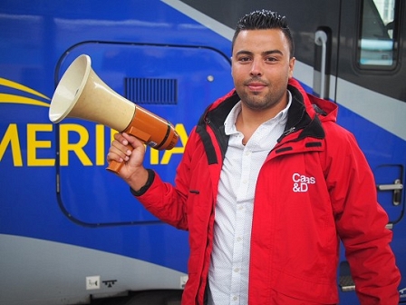 Caritas-Helfer mit Mikrophon am Bahnsteig