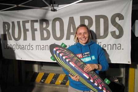 Ruffboards-Mitbegründerin zeigt ein Longboard, das aus einem alten Snowboard gebaut wurde