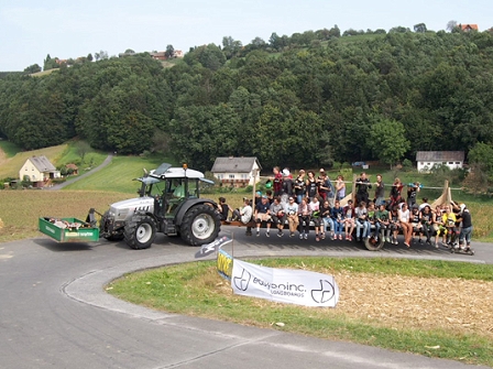 Ein Traktor zieht Longboarder auf einem Anhänger