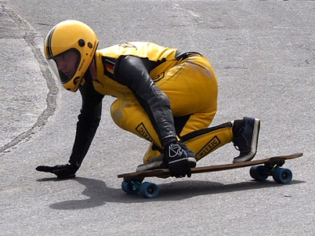 Longboarder in gelber Lederkluft in Kurve