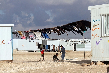 Kinder spielen im Flüchtlingslager Zaatari zwisschen Blechcontainern und aufgehängter Wäsche