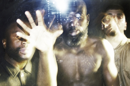 Die Band Young Fathers schaut in die Kamera, einer greift auf die Linse