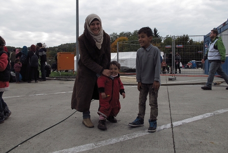 Junge syrische Mutter mit einem Kleinkind. Sie freuen sich. Ein weiterer Sohn, ein Bub, steht daneben und lacht