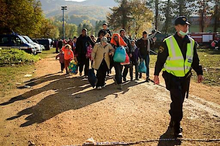 Migrants and asylum seekers walk towards a bus as they leave a refugee centre in Brezice in eastern Slovenia on October 24, 2015.