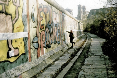 Ein Punk malt eine Linie auf die Berliner Mauer