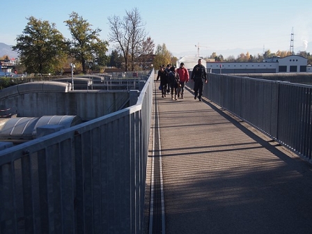 Menschen gehen mit einem Polizisten über eine Brücke