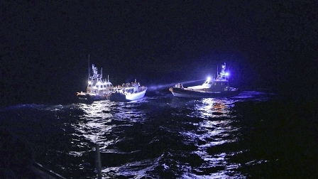 zwei rettungsboote und ein flüchtlingsboot bei nacht am meer