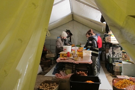 Menschen schneiden Kartoffeln und Gemüse in einem Zelt in der Mobilen Küche in Spielfeld