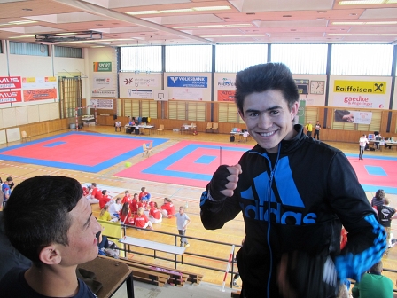 Kickboxer Amiri macht eine Pose neben einem Freund auf der Tribüne in der Sporthalle Köflach