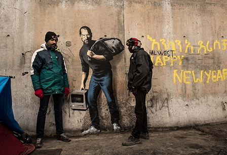 Zwei Flüchtlinge stehen um ein Banksy-Portrait von Steve Jobs