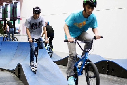 Zwei Jugendliche auf Bike und Roller im Pumptrack-Parcours