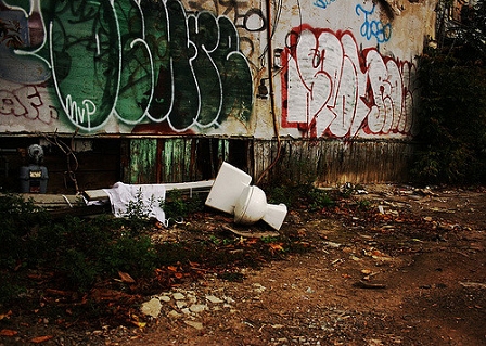 Ein Klo liegt neben einer Mauer mit viel Graffiti.