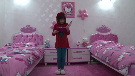 Ein Mädchen trägt Helly-Kitty-Plüschpatschen und steht in einem Kinderzimmer, in dem fast jeder Gegenstand Helly-Kitty-Motive trägt. Filmstill aus "Paradies! Paradies!"