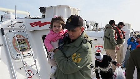 A coast guard holds a child in his arms as he gets off a Turkish Coast guard boat near the village of Kucukkuyu, in western Turkey.