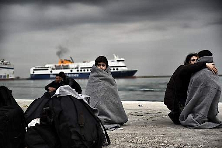 Children wrapped in covers stand in a harbour as migrants and refugees arrive on the Greek island of Lesbos while crossing the Aegean Sea from Turkey on March 2, 2016, in Mytilene.