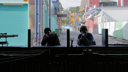 Zwei Männer mit Schießgewehren an einer Art Vergnügungsstand; Filmstill aus "Endzeit"