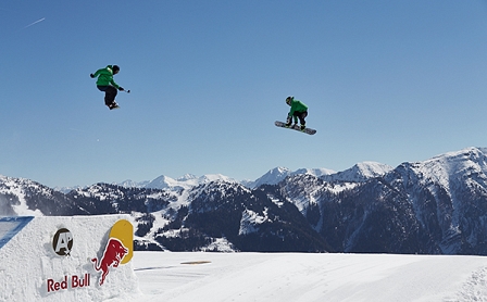 Zwei Snowboarder springenüber eine Schanze