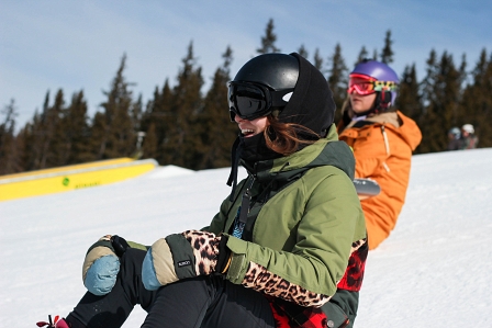 Zwei Riderinnen sitzen auf der Piste und lächeln