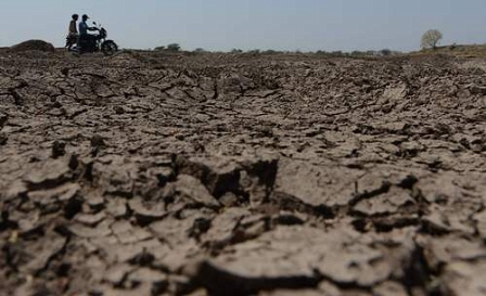 Global Warming: Indian villagers ride a motorcycle across the dried bed of the Shitala Lake at Umrala village in Botad district, some 150 kms from Ahmedabad