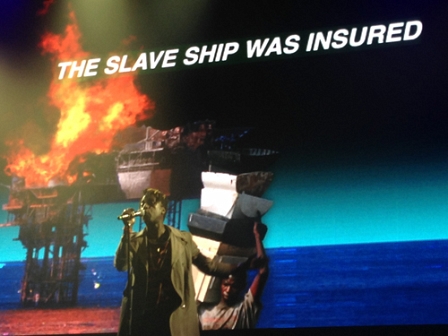 Saul Williams vor einer Visualisierung mit der Aufschrift: The Slave Ship was insured