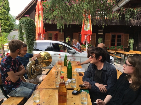 Die zwei steirischen Musiker und Der Nino aus Wien und Natalie Ofenböck sitzen auf Bierbänken, daneben steht ein Auto, denn im CD-Player im Auto läuft ihre Musik